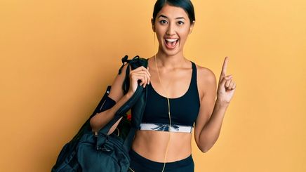 A beautiful Asian woman with a big smile holding a black gym bag