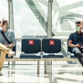Two Asian men social distancing in airport