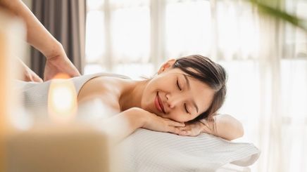  Smiling woman closing her eyes in relaxation while getting a lymphatic drainage massage.