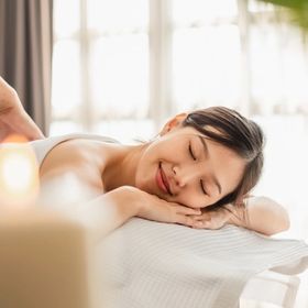  Smiling woman closing her eyes in relaxation while getting a lymphatic drainage massage.