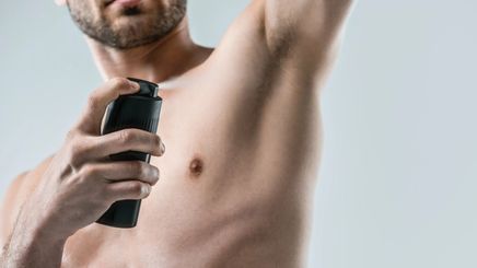 Man spraying deodorant on his body 