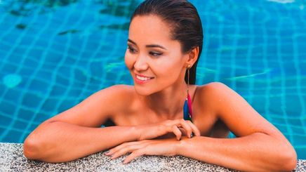 Asian woman with wet hair hanging out in a swimming pool.