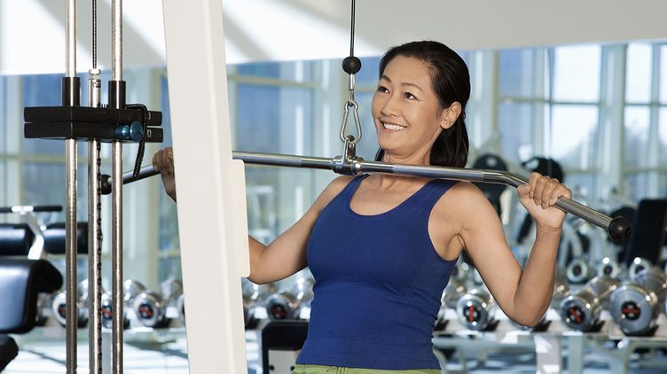 A smiling Asian woman wearing blue at the gym