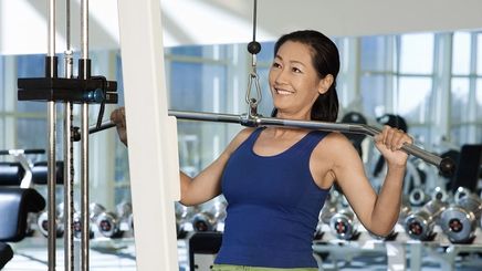 A smiling Asian woman wearing blue at the gym