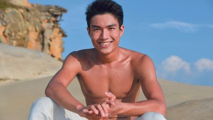 Handsome Asian man without shirt and sitting on the beach