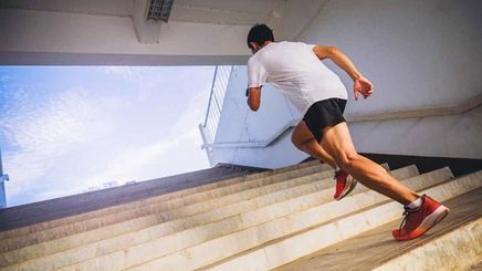 A man with toned, muscled legs sprinting up a flight of stairs.