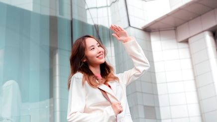 Smiling woman in business suit covering her head with her hand from the sun.