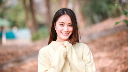 Asian woman in a yellow sweater smiling straight at the camera.