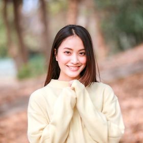 Asian woman in a yellow sweater smiling straight at the camera.