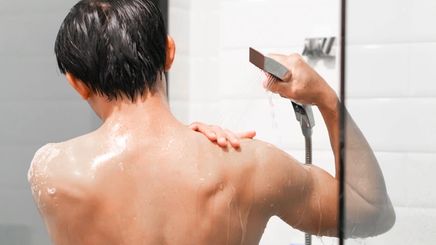 Back of an Asian man showering.