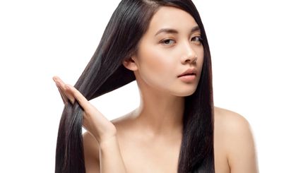An Asian woman touching her long, healthy hair