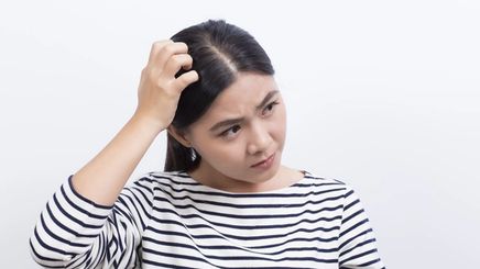 Asian woman in striped shirt touching head
