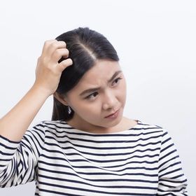 Asian woman in striped shirt touching head