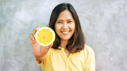 Asian woman holding half an lemon
