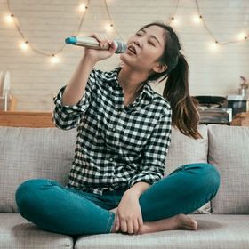 Asian woman singing solo on couch 