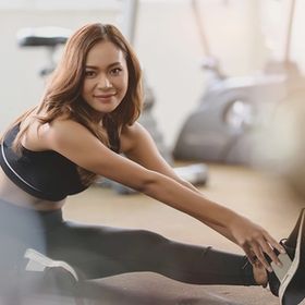 A beautiful Asian woman stretching at the gym