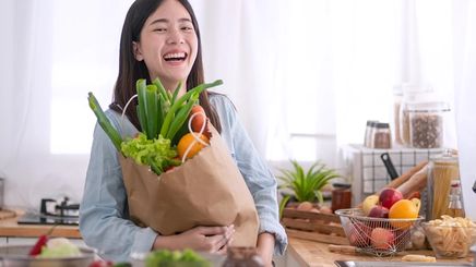 Asian woman holding a bag of vegetables