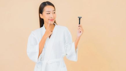 An Asian woman holding a razor with her left hand