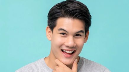 happy smiling young Asian man with hand on his chin 