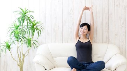 A beautiful Asian woman stretching her arms on a couch
