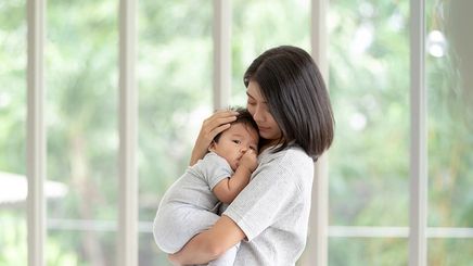 Asian mom carrying newborn