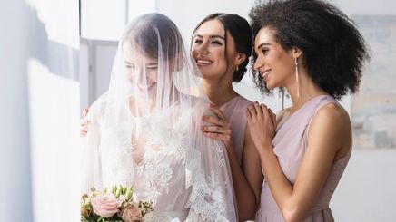 A bride and two bridesmaids smiling together.