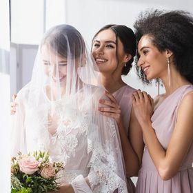 A bride and two bridesmaids smiling together.