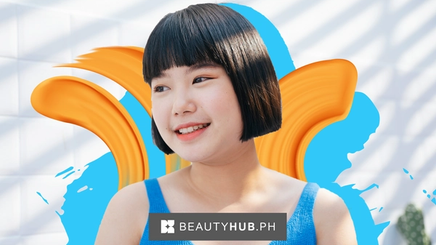 An Asian girl with a short bob smiling under the sun