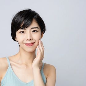 Asian woman with short hair touching her face