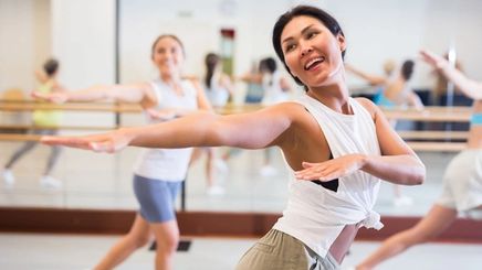 Middle-aged Asian woman dancing with group.