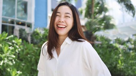 Woman in white shirt smiling widely to the camera.