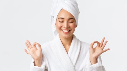 Asian woman in a robe smiling while meditating