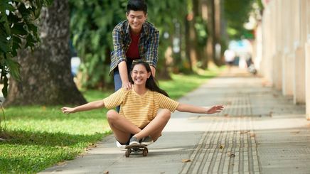 Asian man with woman on skateboard