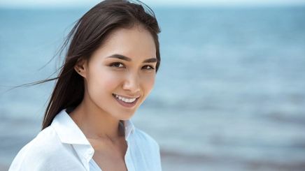 Closeup of an Asian woman wearing a white shirt by the beach