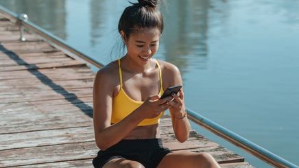 Sweaty Asian woman sitting on a wooden bridge with phone