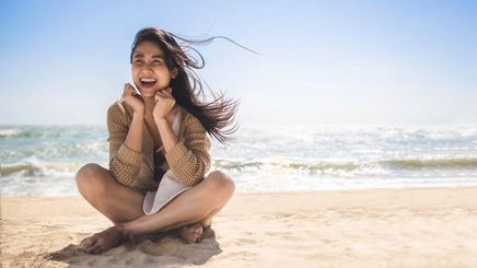 Asian woman with long hair sitting on the beach