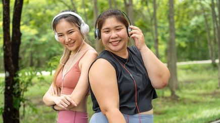 Two Asian women in workout clothes and headphones.
