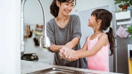 Asian mother and daughter washing hands in the kitchen