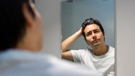Handsome Asian man looking at himself in the mirror