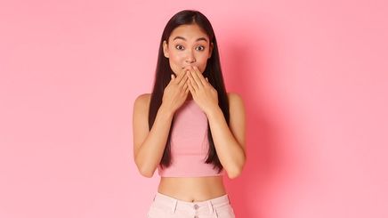 Asian woman covers her mouth with both hands