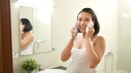 Pregnant Asian woman washing face
