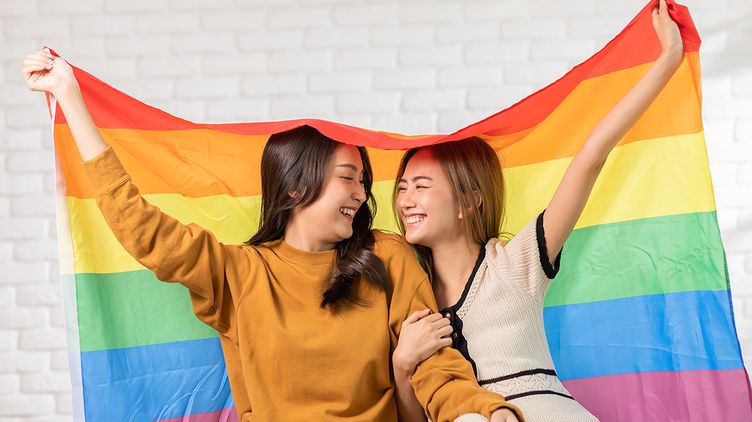 LGBT Asian couple holding up the Pride flag