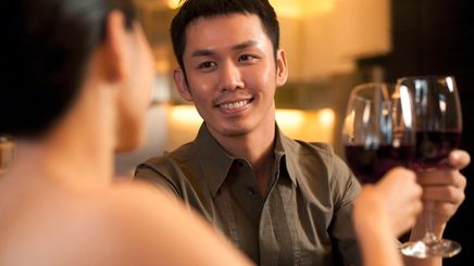 Asian man toasting wine on date.