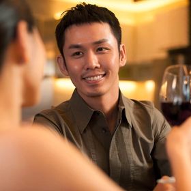 Asian man toasting wine on date.
