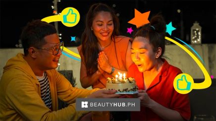 Asian woman blowing birthday cake with friends.