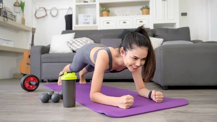 Fit Asian woman doing planks on a purple mat at home