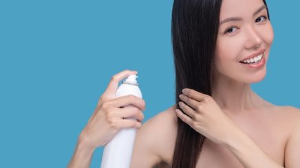Filipino woman spraying hair with white bottle