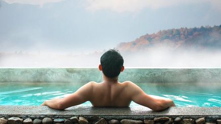 Back of an Asian man relaxing in a hot bath.