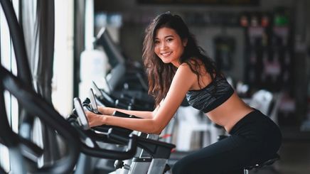 Woman with long hair riding an exercise bike at the gym.
