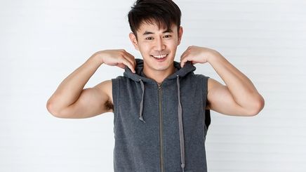 Asian man in sleeveless gray hoodie